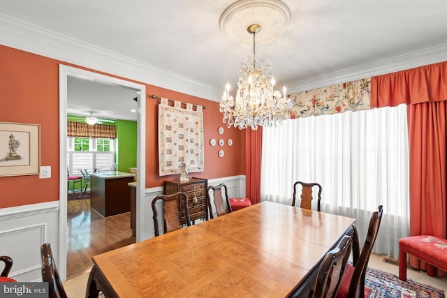 dining room with a chandelier, ornamental molding, and a wainscoted wall