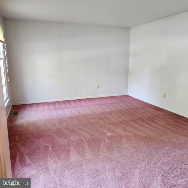 empty room featuring carpet and baseboards