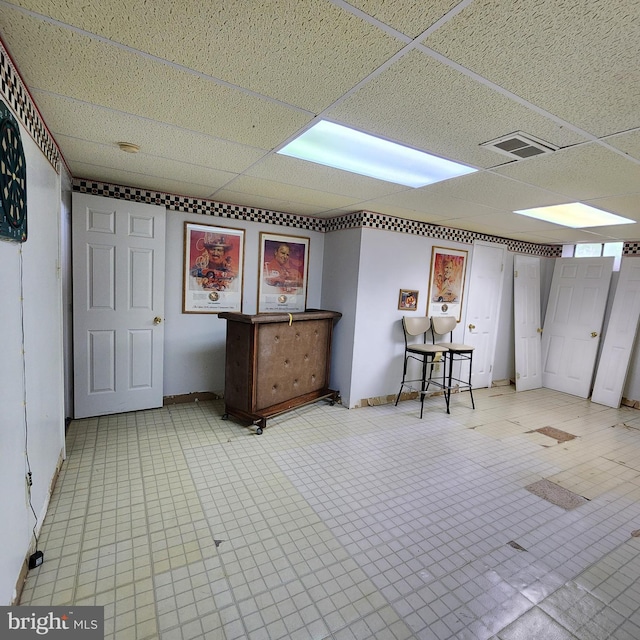 below grade area featuring a drop ceiling, tile patterned floors, and baseboards
