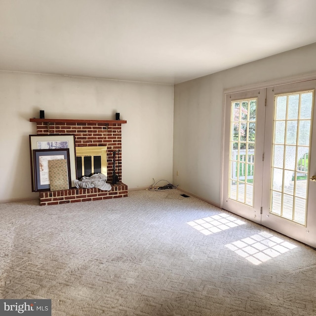 unfurnished living room featuring carpet and a brick fireplace
