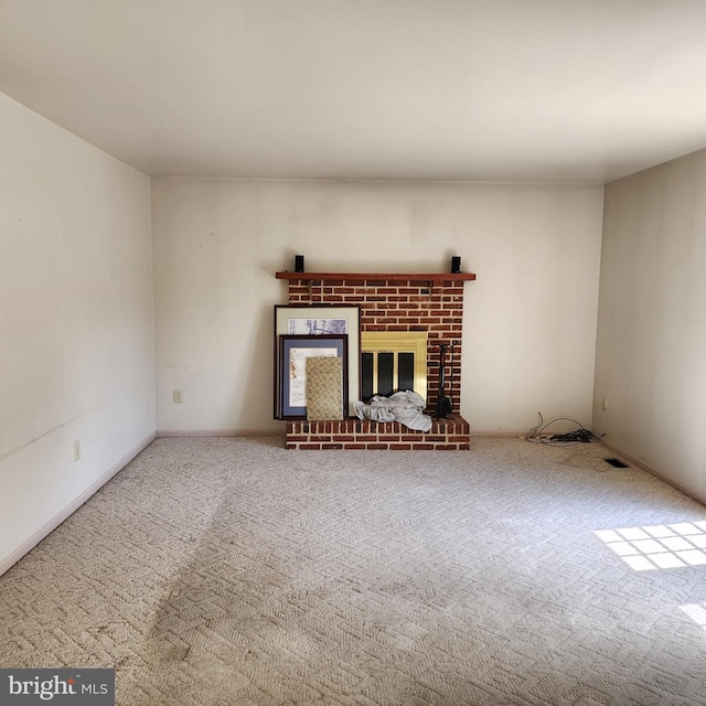 unfurnished living room featuring carpet flooring and a brick fireplace