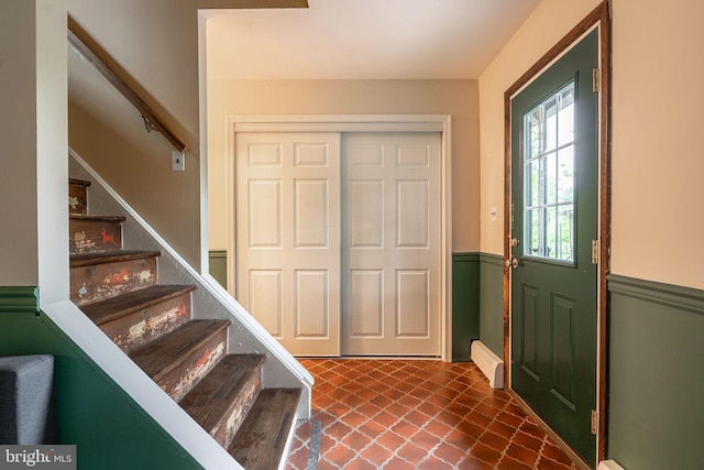 foyer entrance with stairway and a baseboard radiator