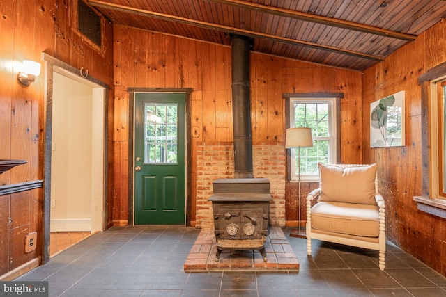 sitting room featuring a wood stove, lofted ceiling, wood ceiling, wooden walls, and tile patterned flooring