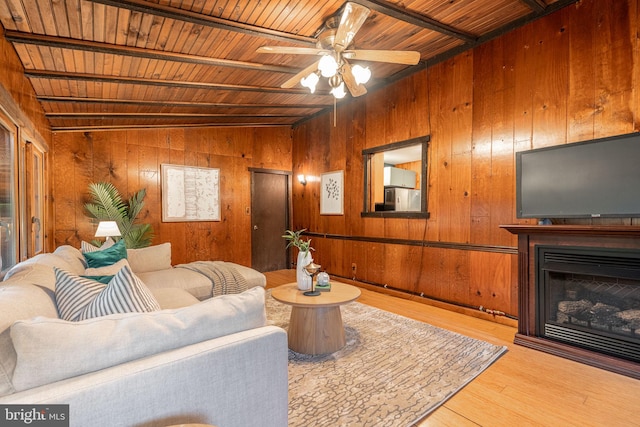 living area featuring wood ceiling, wood walls, wood finished floors, a fireplace, and a ceiling fan