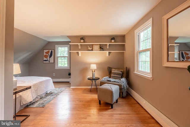 bedroom with baseboard heating, light wood-type flooring, lofted ceiling, and baseboards