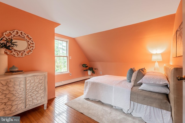 bedroom with baseboard heating, hardwood / wood-style floors, and vaulted ceiling