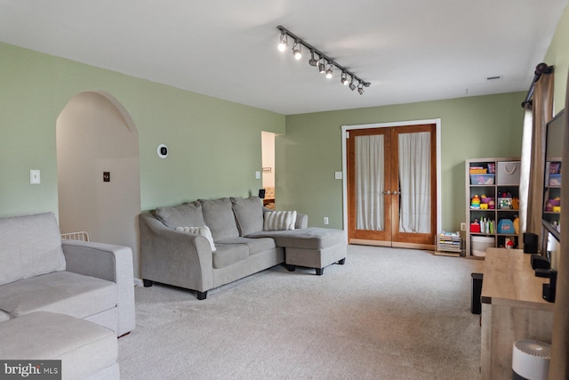 living room with carpet flooring, track lighting, and arched walkways