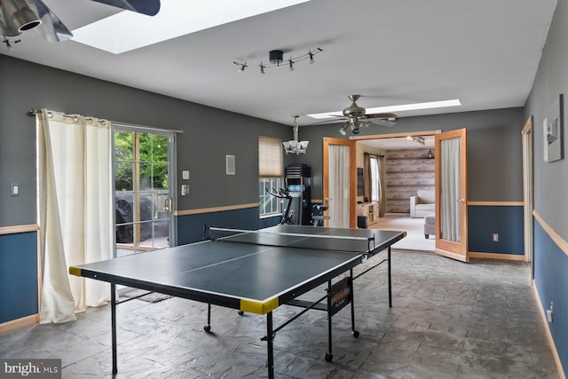 rec room featuring a skylight, ceiling fan, baseboards, and a chandelier