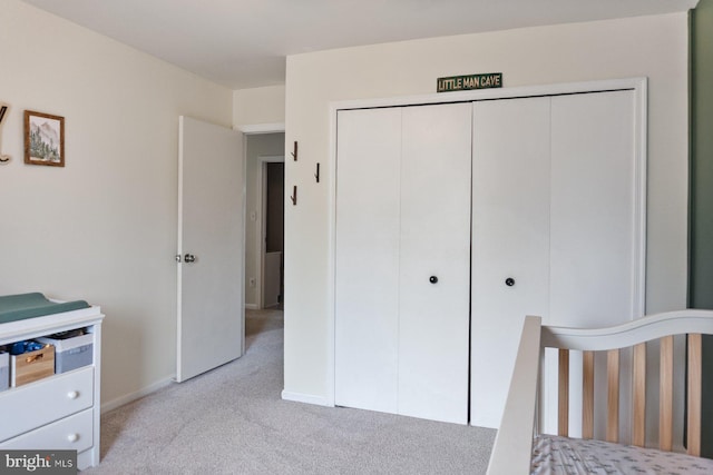 bedroom with light colored carpet, a closet, and baseboards