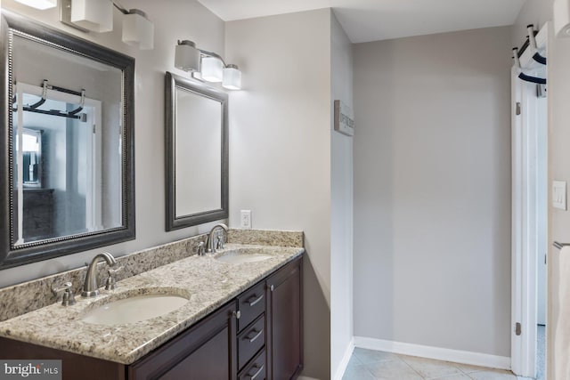 bathroom with double vanity, baseboards, and tile patterned floors