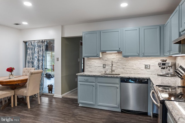 kitchen with appliances with stainless steel finishes, a sink, backsplash, recessed lighting, and dark wood-style flooring