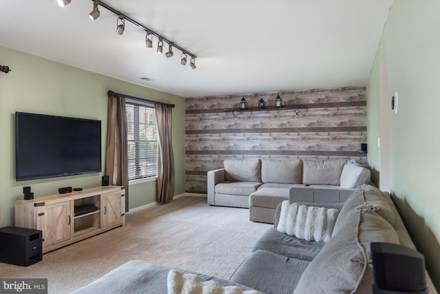 living room featuring light colored carpet, wooden walls, rail lighting, and baseboards