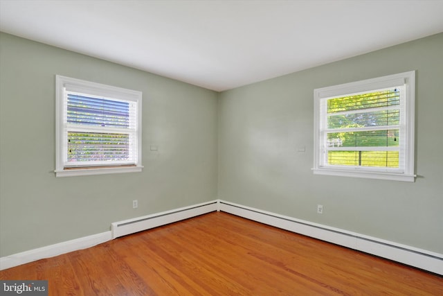 empty room with baseboards, wood finished floors, a baseboard heating unit, and a baseboard radiator