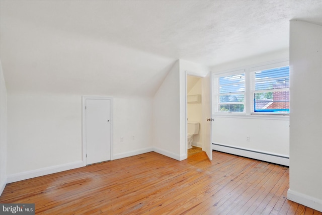 bonus room with a baseboard heating unit, light wood-style floors, lofted ceiling, baseboards, and an AC wall unit