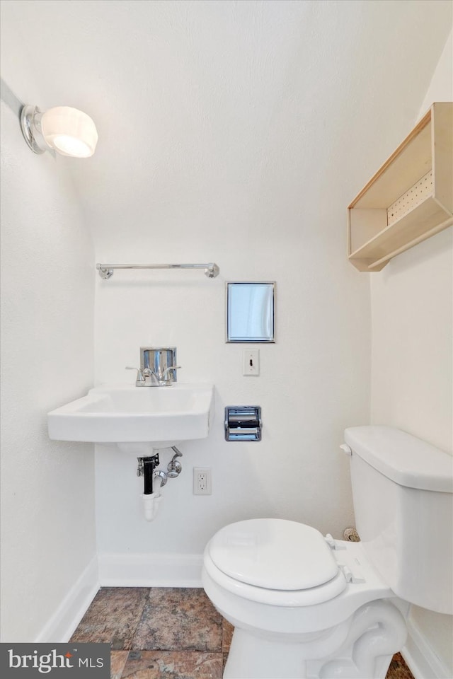 half bathroom featuring toilet, baseboards, and a sink