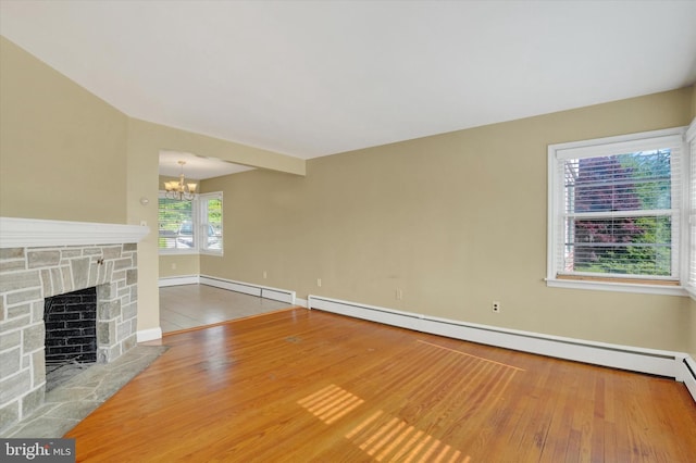 unfurnished living room featuring a chandelier, wood finished floors, baseboards, and a fireplace