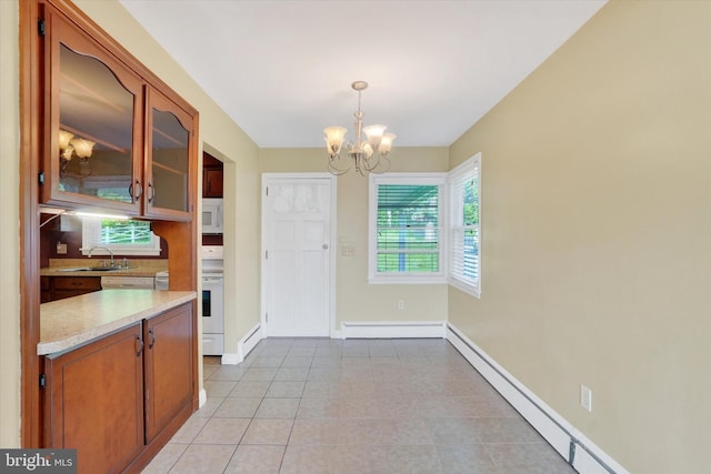 unfurnished dining area featuring a baseboard heating unit, a chandelier, baseboards, and a sink