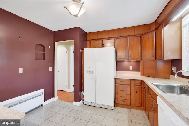 kitchen with white appliances, a sink, light countertops, a baseboard heating unit, and brown cabinetry