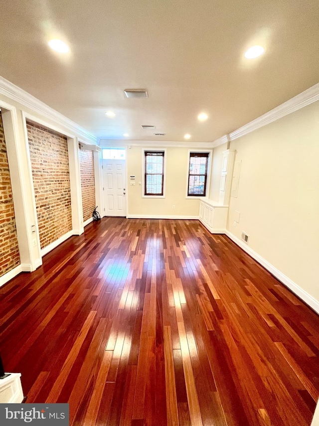 spare room featuring hardwood / wood-style floors, ornamental molding, baseboards, brick wall, and recessed lighting