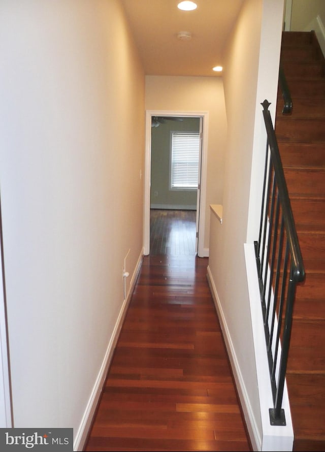 hallway with wood finished floors, stairs, baseboards, and recessed lighting