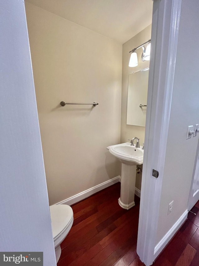 bathroom with hardwood / wood-style flooring, toilet, and baseboards