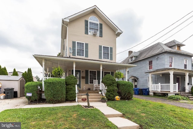 view of front of home with a porch, a storage shed, an outbuilding, and a front lawn