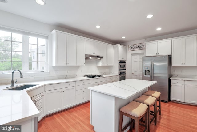 13626 Sylvan Bluff Dr, Leesburg, VA 20176 - kitchen with stainless steel appliances, under cabinet range hood, white cabinetry, light wood-style flooring, and recessed lighting