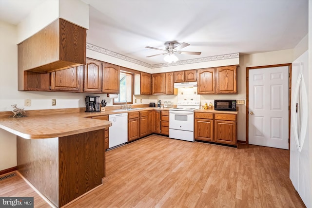 13245 Croom Rd, Upper Marlboro, MD 20772 - kitchen with white appliances, under cabinet range hood, a peninsula, and brown cabinetry
