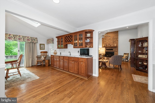 kitchen featuring lofted ceiling, a skylight, wood finished floors, glass insert cabinets, and a fireplace
