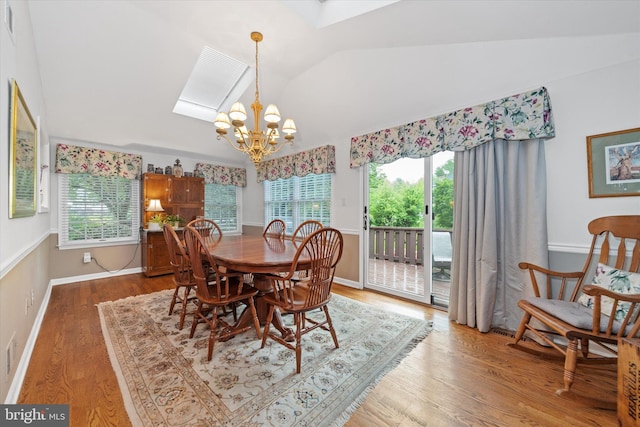 dining room featuring lofted ceiling, a chandelier, plenty of natural light, wood finished floors, and a skylight