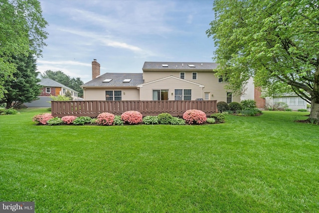 back of house featuring a deck, a yard, and a chimney