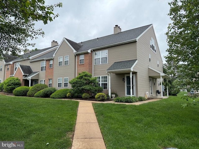 view of front of property featuring a front lawn, a chimney, and roof with shingles