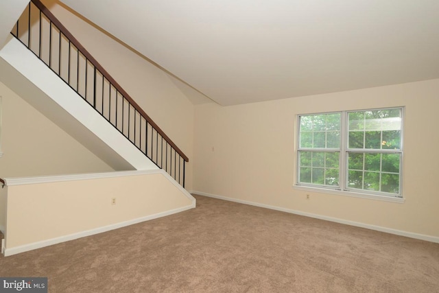 unfurnished living room with carpet, stairs, and baseboards