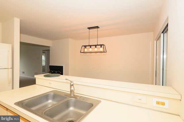 kitchen featuring a sink, freestanding refrigerator, light countertops, and decorative light fixtures