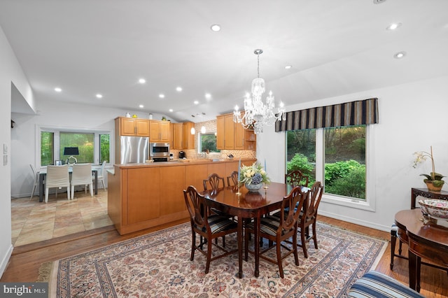 dining space with a chandelier, recessed lighting, light wood-style flooring, baseboards, and lofted ceiling