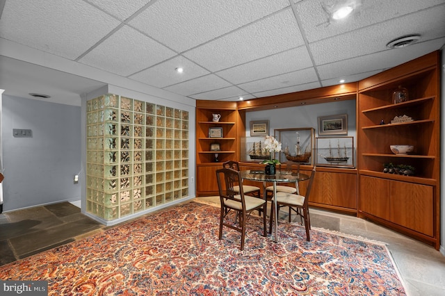 dining area with built in features, a drop ceiling, and recessed lighting