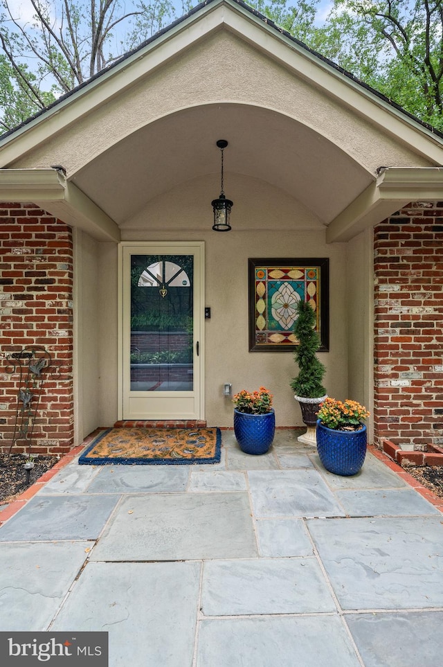 entrance to property featuring brick siding and stucco siding