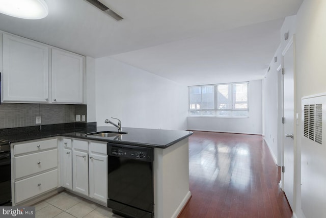 kitchen with black dishwasher, a sink, a heating unit, a peninsula, and white cabinetry