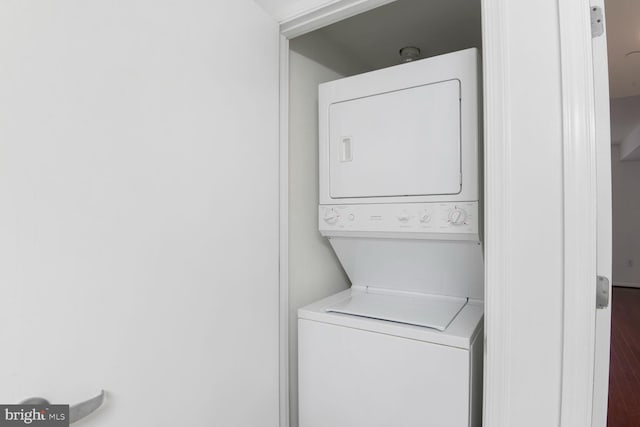 washroom featuring stacked washing machine and dryer and wood finished floors