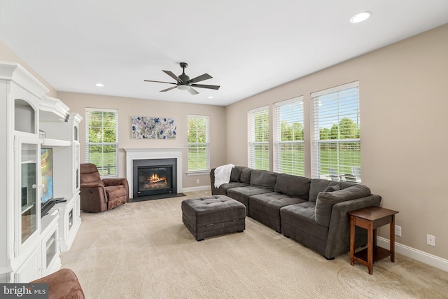 living area with baseboards, light colored carpet, ceiling fan, a fireplace with flush hearth, and recessed lighting