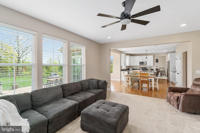 living room with a ceiling fan, recessed lighting, light carpet, and light wood finished floors