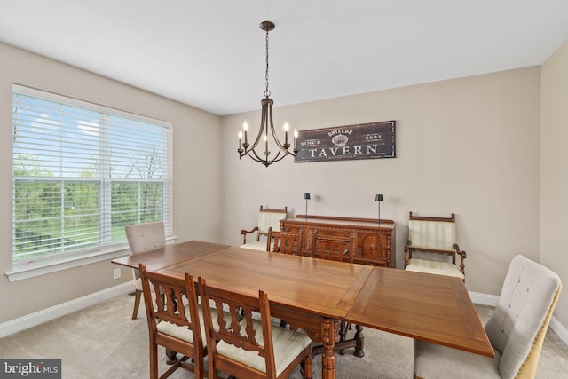 dining room featuring baseboards, a chandelier, and light carpet