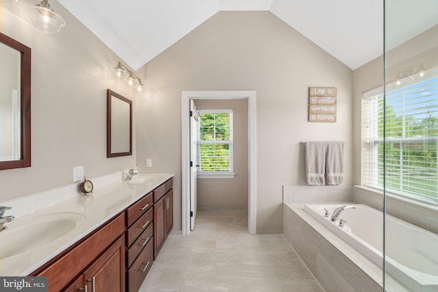 bathroom with healthy amount of natural light, vaulted ceiling, a garden tub, and double vanity