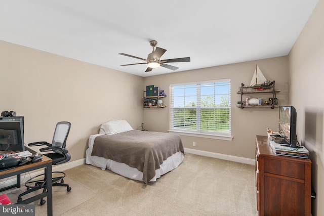 bedroom featuring baseboards, light carpet, an office area, and a ceiling fan