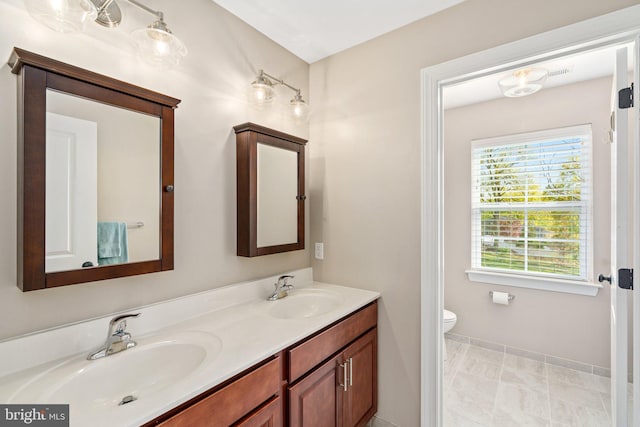 full bath with double vanity, baseboards, and toilet