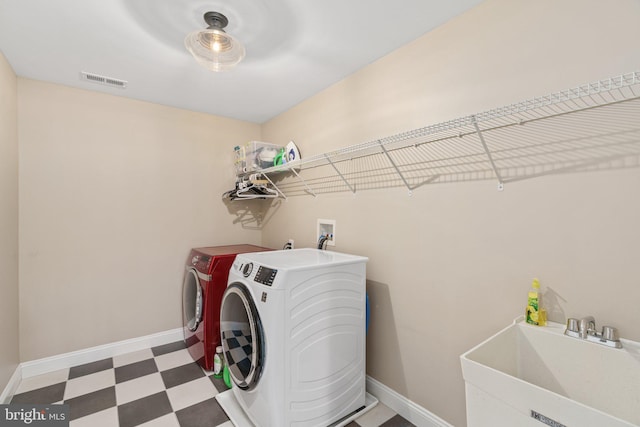 clothes washing area featuring independent washer and dryer, tile patterned floors, and baseboards