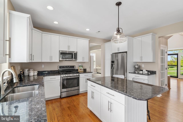 kitchen with stainless steel appliances, a sink, white cabinetry, light wood-style flooring, and recessed lighting
