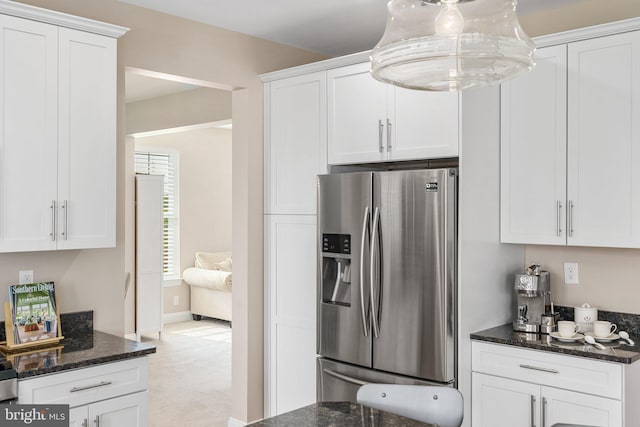 kitchen with stainless steel refrigerator with ice dispenser, white cabinetry, dark stone counters, and light colored carpet