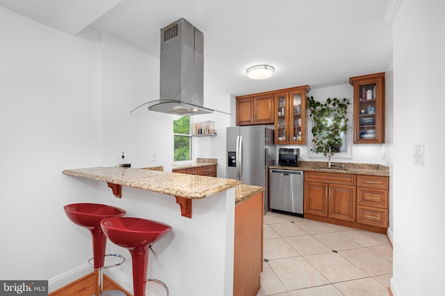 4204 13th Pl NE, Washington, DC 20017 - kitchen featuring appliances with stainless steel finishes, range hood, brown cabinetry, a sink, and a breakfast bar