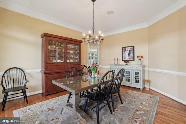 dining room with a chandelier, wood finished floors, crown molding, and baseboards